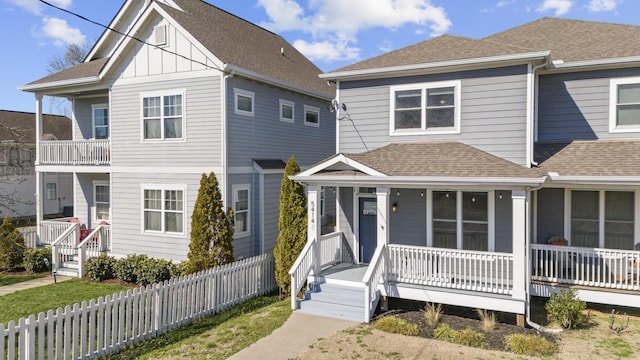 view of front of home featuring a porch, fence, and roof with shingles