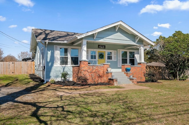 view of front of home with brick siding, covered porch, a front yard, and fence