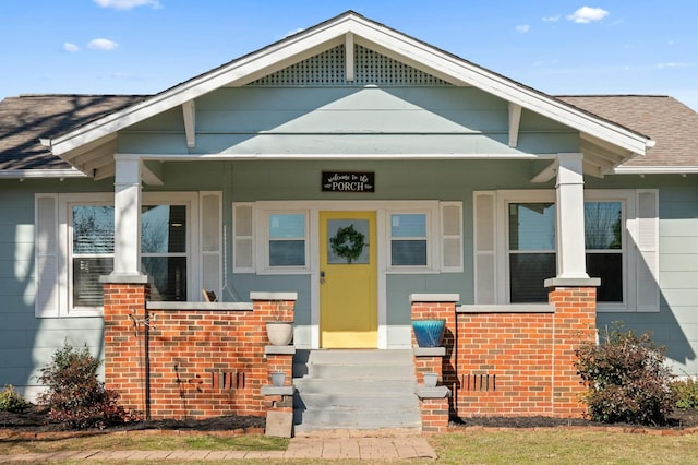 property entrance featuring brick siding and roof with shingles