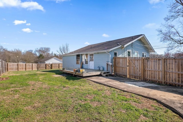 rear view of property with a lawn, a fenced backyard, and a gate