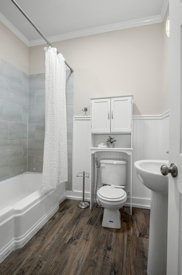 bathroom featuring wood finished floors, a wainscoted wall, ornamental molding, shower / bath combo with shower curtain, and toilet