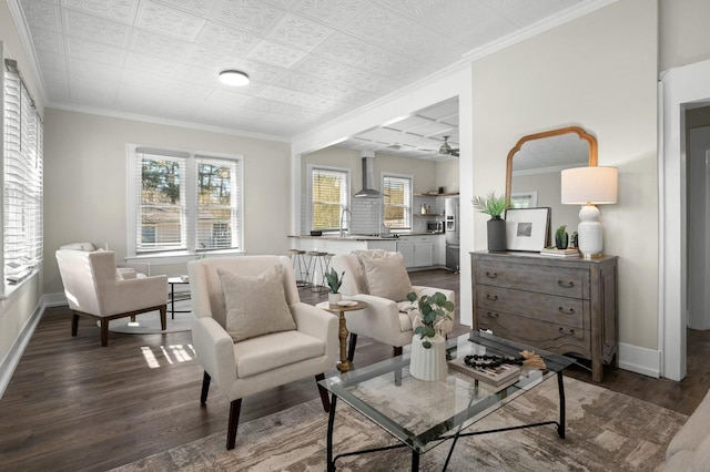 living room featuring baseboards, a healthy amount of sunlight, wood finished floors, and crown molding