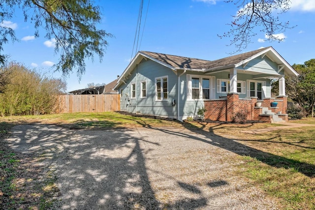 exterior space with brick siding, covered porch, and fence