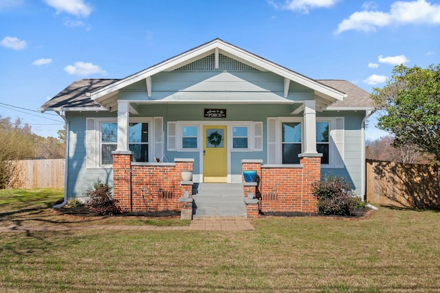 view of front of home featuring a front yard, covered porch, fence, and brick siding