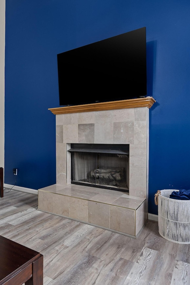 interior details featuring wood finished floors, baseboards, and a tile fireplace