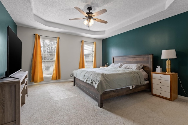 bedroom featuring a tray ceiling, carpet flooring, baseboards, and a textured ceiling