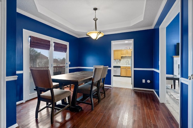 dining space with a textured ceiling, a raised ceiling, baseboards, and dark wood-style flooring