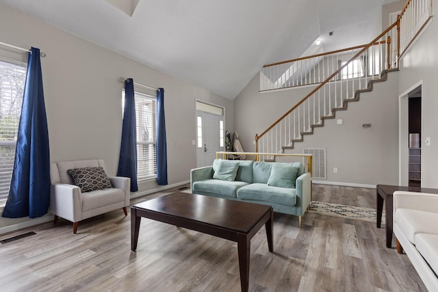 living room with light wood finished floors, visible vents, and stairs