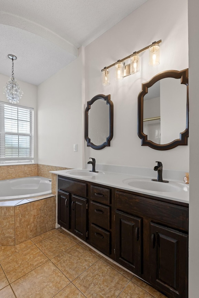 full bathroom with a bath, tile patterned flooring, a textured ceiling, and a sink