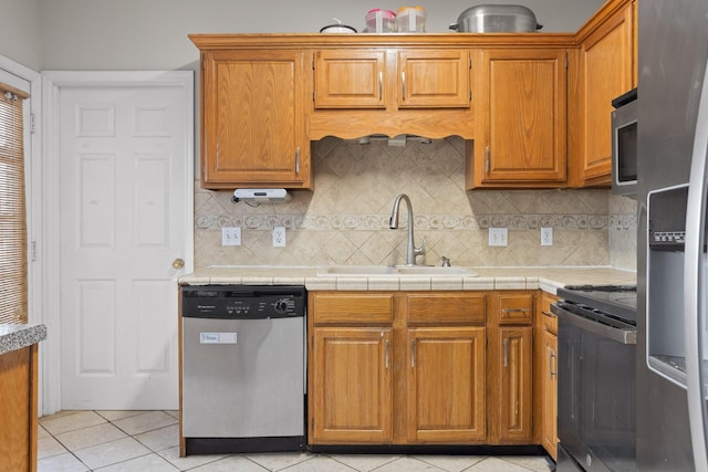 kitchen featuring light tile patterned floors, a sink, light countertops, appliances with stainless steel finishes, and tasteful backsplash