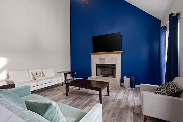 living area with baseboards, lofted ceiling, wood finished floors, and a fireplace