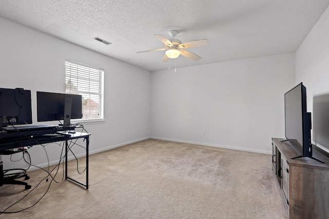 office space featuring a ceiling fan, visible vents, baseboards, a textured ceiling, and carpet flooring