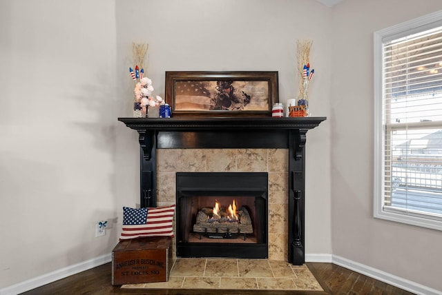 interior details featuring wood finished floors, baseboards, and a tile fireplace