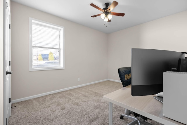 carpeted office with baseboards and a ceiling fan