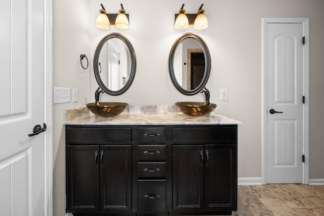 full bathroom with double vanity, baseboards, and a sink