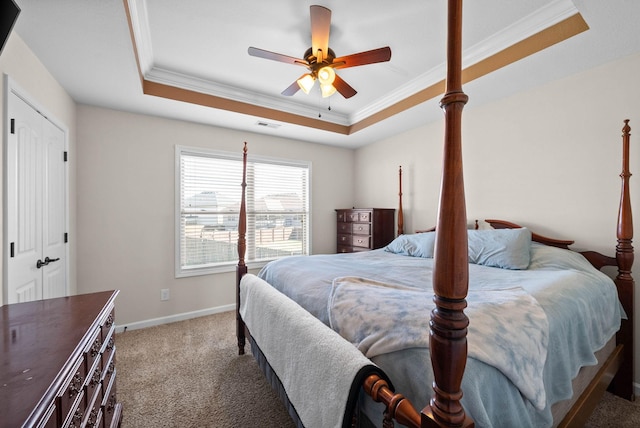 carpeted bedroom featuring a tray ceiling, a ceiling fan, baseboards, and ornamental molding