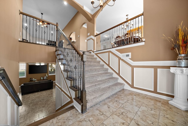 stairway featuring arched walkways, visible vents, an inviting chandelier, and a towering ceiling