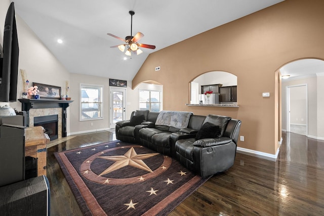 living room with dark wood finished floors, high vaulted ceiling, arched walkways, and a tile fireplace