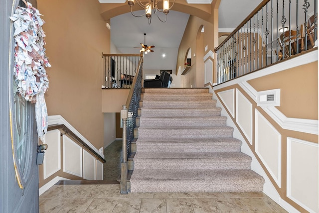 staircase with a high ceiling and a ceiling fan