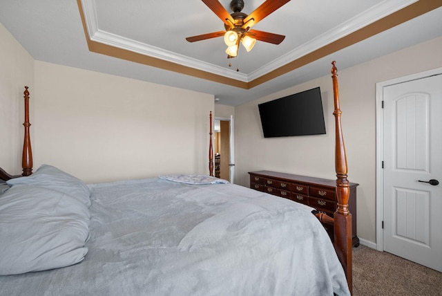 carpeted bedroom with ceiling fan, baseboards, a tray ceiling, and ornamental molding