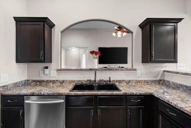 kitchen featuring a ceiling fan, arched walkways, a sink, stainless steel dishwasher, and dark countertops