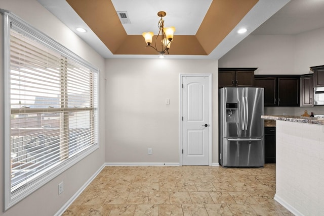 kitchen featuring a raised ceiling, dark brown cabinetry, appliances with stainless steel finishes, baseboards, and hanging light fixtures