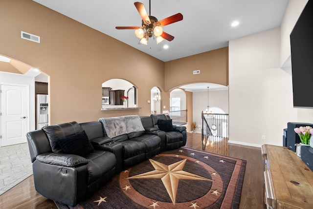 living room with visible vents, arched walkways, high vaulted ceiling, and wood finished floors