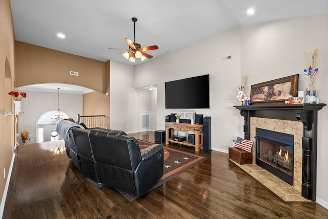 living room with wood finished floors, visible vents, baseboards, arched walkways, and a tiled fireplace