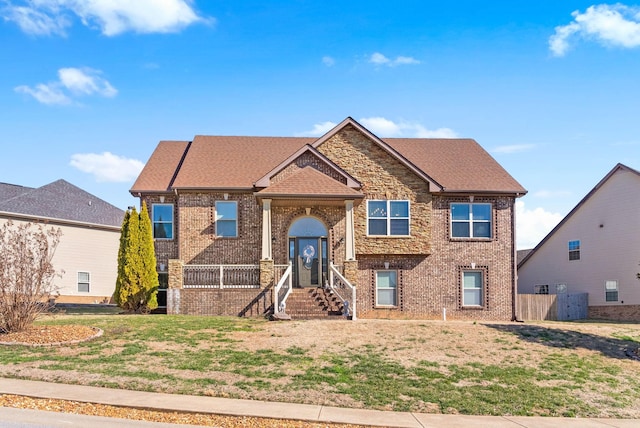 view of front of home with a front yard, brick siding, and a shingled roof