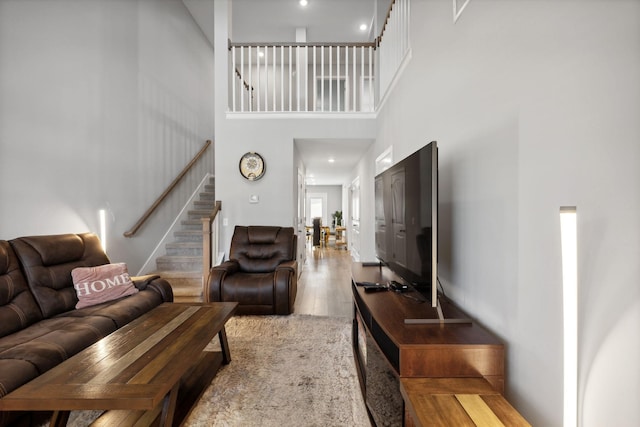 living room with stairway, a towering ceiling, and wood finished floors