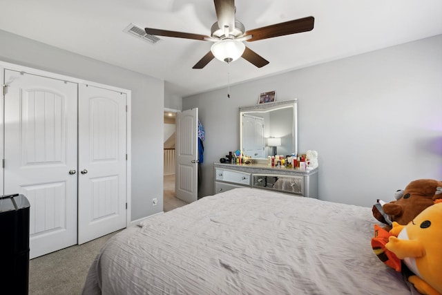 carpeted bedroom with a closet, visible vents, and a ceiling fan