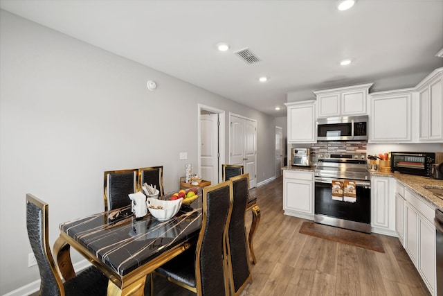 kitchen with white cabinets, light wood-style floors, visible vents, and stainless steel appliances