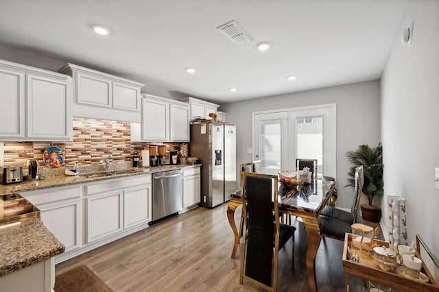 kitchen with light wood finished floors, visible vents, appliances with stainless steel finishes, white cabinetry, and a sink