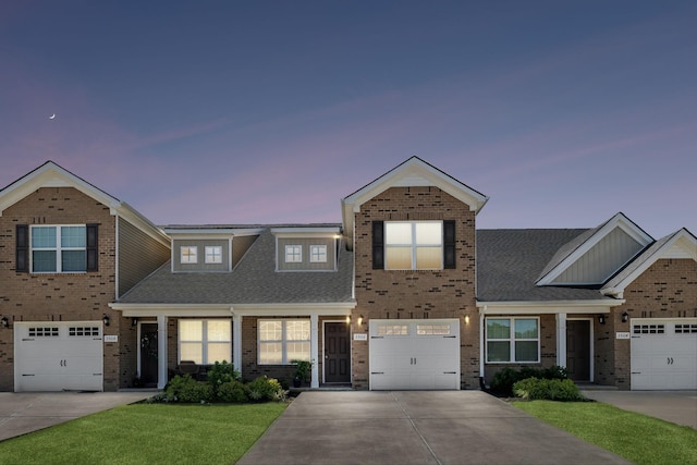 view of front facade featuring concrete driveway, a lawn, brick siding, and roof with shingles