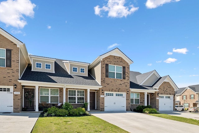 view of front of house featuring a front lawn, driveway, roof with shingles, an attached garage, and brick siding