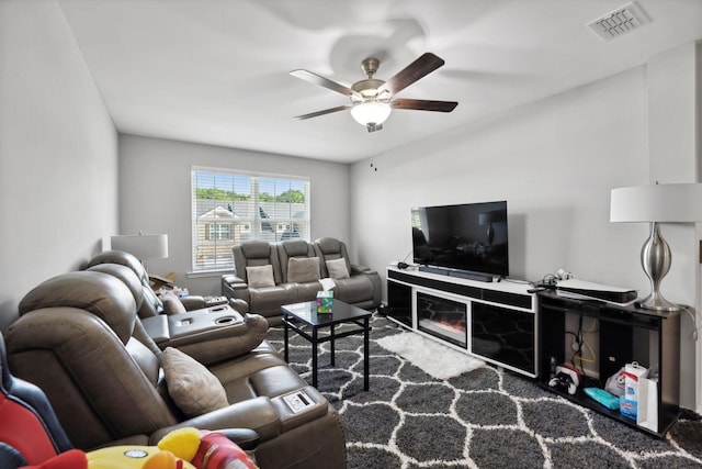 living room featuring a glass covered fireplace, a ceiling fan, visible vents, and carpet floors