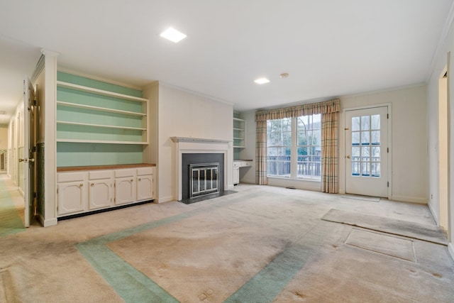 unfurnished living room with light carpet, a fireplace with flush hearth, crown molding, and built in features