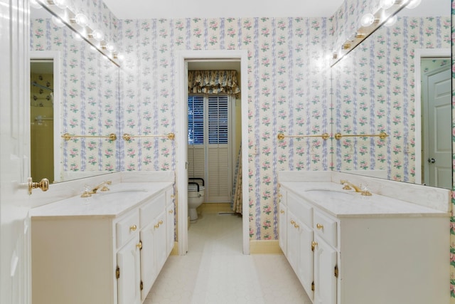 bathroom with a sink, two vanities, and wallpapered walls