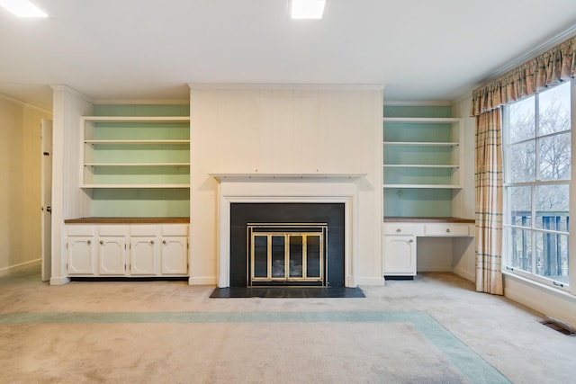 unfurnished living room featuring baseboards, visible vents, a fireplace with flush hearth, ornamental molding, and carpet flooring