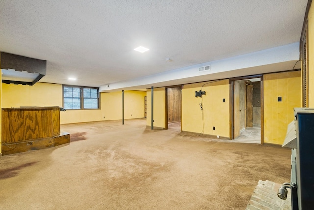 below grade area with light carpet, visible vents, and a textured ceiling