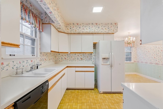 kitchen featuring wallpapered walls, a sink, light countertops, white fridge with ice dispenser, and dishwasher