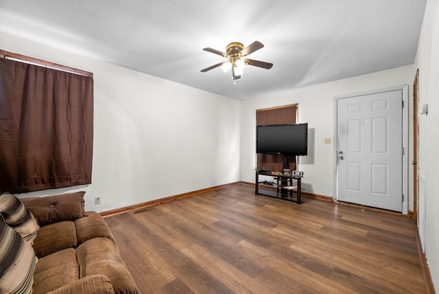 living area with a ceiling fan, visible vents, wood finished floors, and baseboards