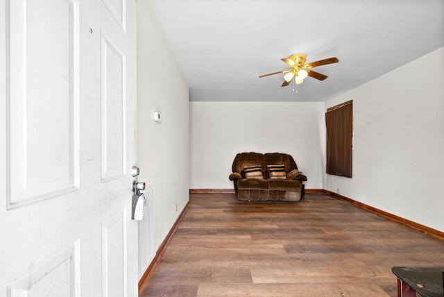 living area featuring ceiling fan, baseboards, and wood finished floors