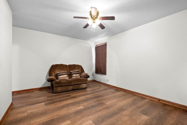 living area featuring a ceiling fan, visible vents, wood finished floors, and baseboards