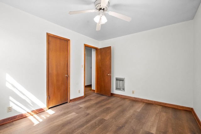 unfurnished bedroom with heating unit, wood finished floors, baseboards, and ceiling fan