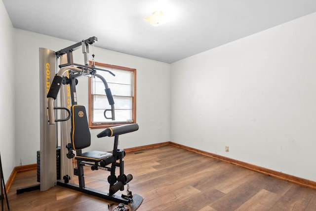 exercise room with baseboards and wood finished floors