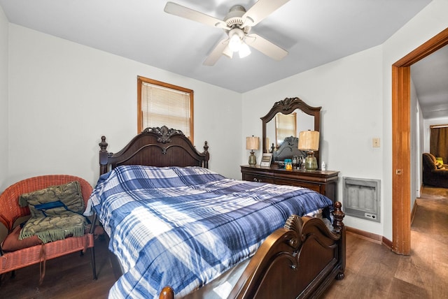 bedroom featuring a ceiling fan, heating unit, wood finished floors, and baseboards