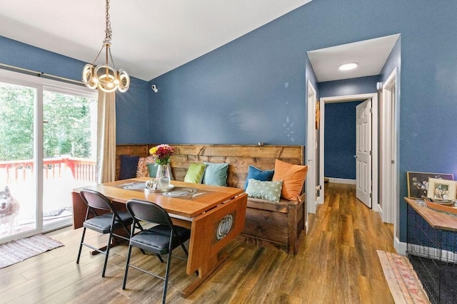 dining space with baseboards, an inviting chandelier, and wood finished floors