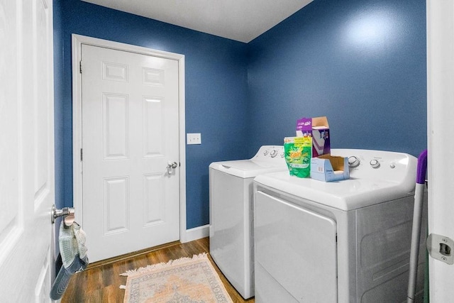 washroom with baseboards, wood finished floors, laundry area, and washing machine and clothes dryer