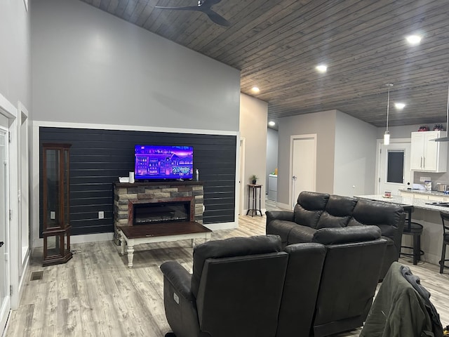 living room with a ceiling fan, light wood-style flooring, recessed lighting, a fireplace, and wood ceiling